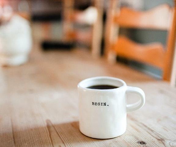 starting a business coffee cup with the words begin sitting on kitchen table 