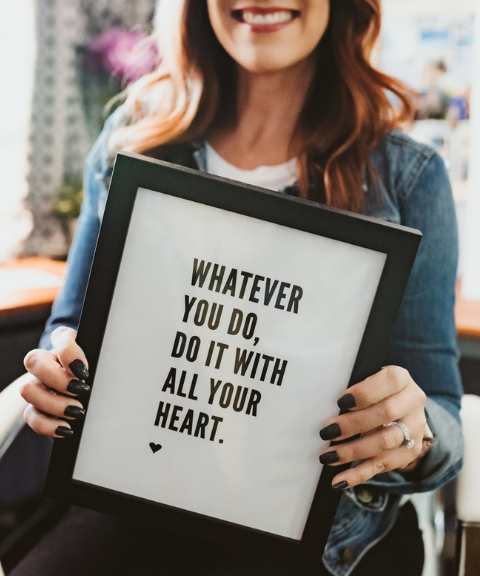 Why hire a personal brand coach Heather Piazza in her office holding framed print whatever you do do it with all your heart