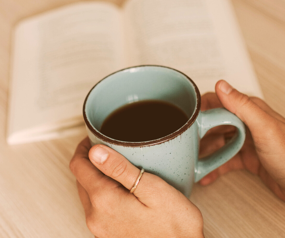 what to do when your brand feels off woman holding coffee while reading book